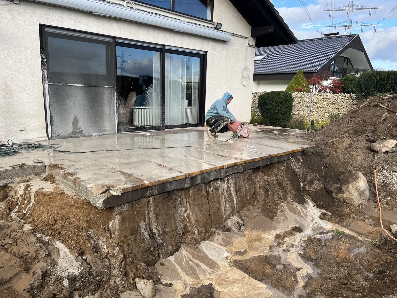 Freigelegte Betonterrasse an der Hauswand, Erdreich darunter geöffnet