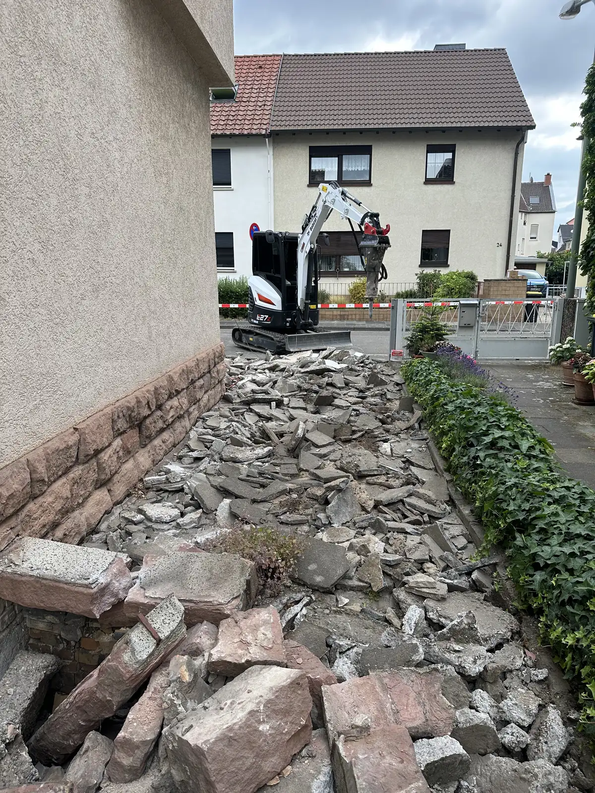 Aufgebrochener alter Weg neben der Hauswand, Bruchstücke und Schutt