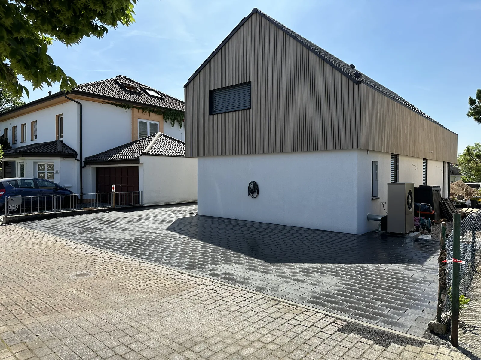 Fertig gepflasterte Hoffläche vor einem holzverkleideten Neubau