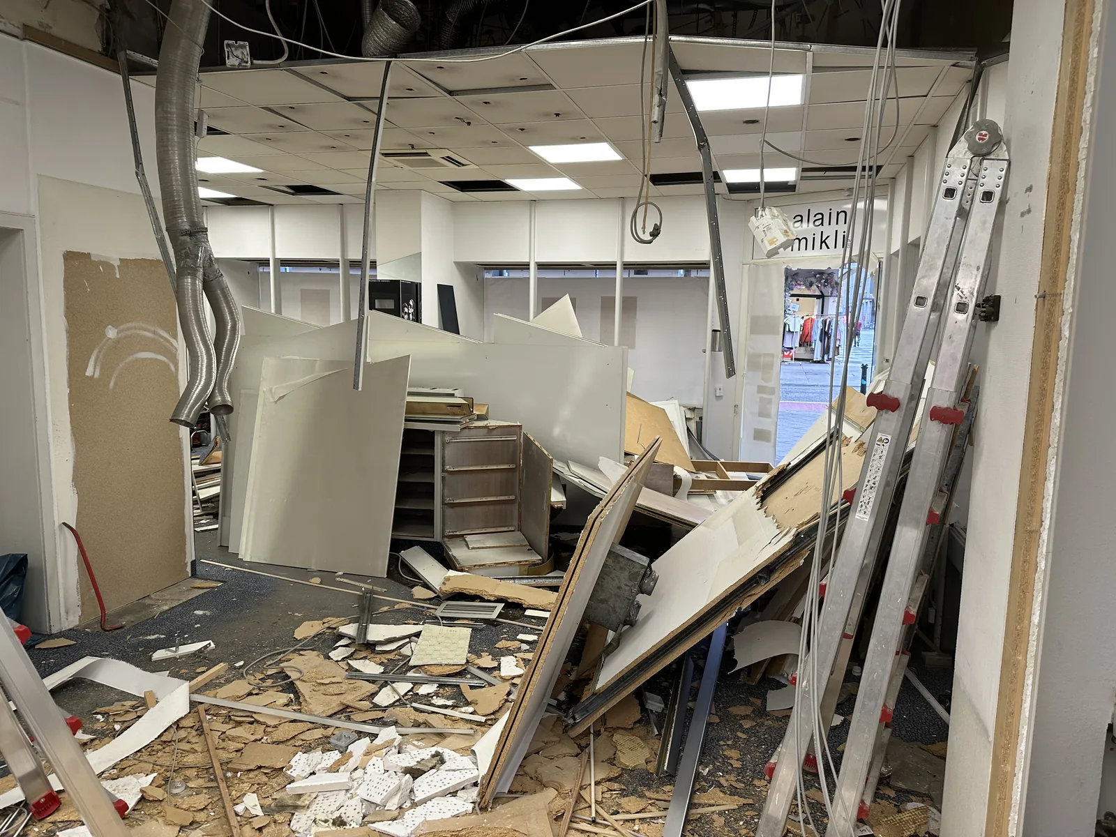 Ladenlokal in der Entkernung: geöffnete Decke, freiliegende Installation, Bauschutt am Boden