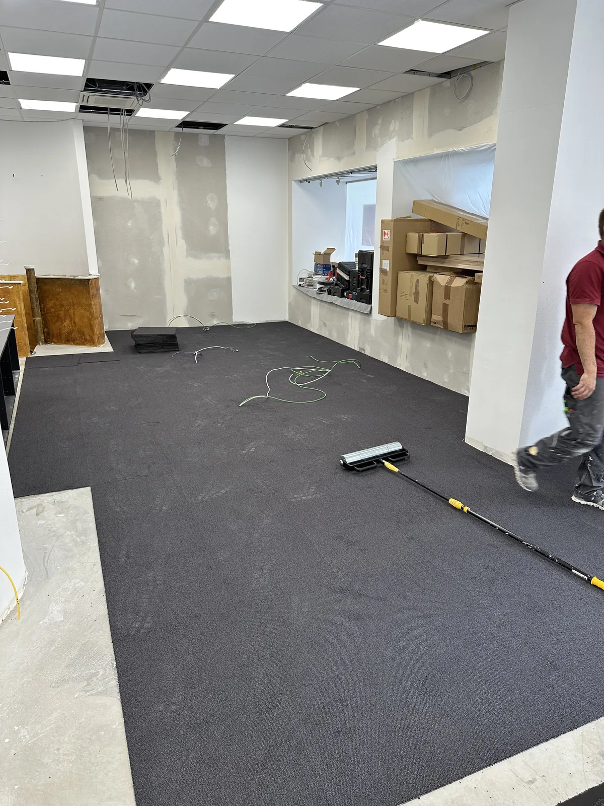 Dunkelgraue Teppichfliesen werden im fertig ausgebauten Verkaufsraum verlegt