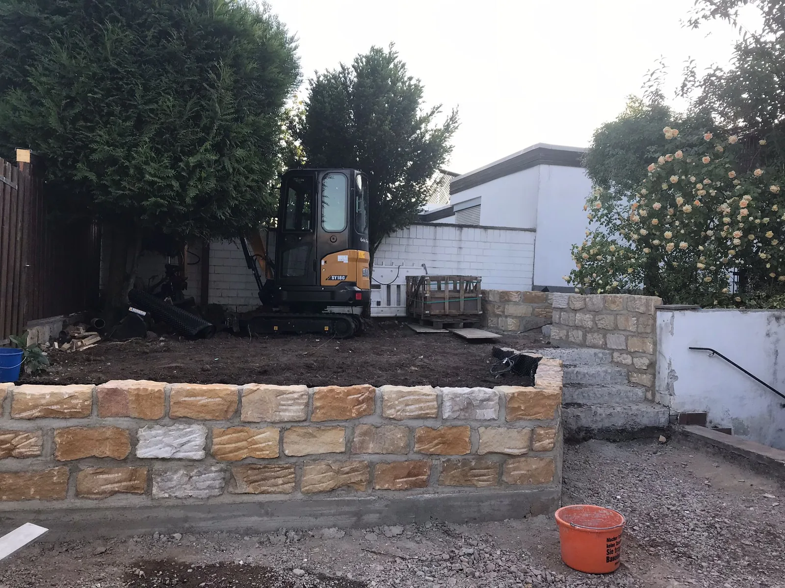 Erste Lagen einer Natursteinmauer im Garten, Steine noch unverfugt