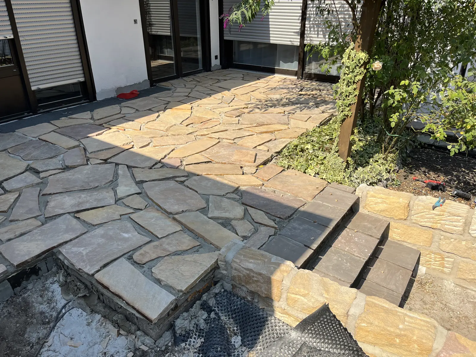 Natursteinterrasse mit Polygonalplatten und angrenzender Treppe, fertig verfugt