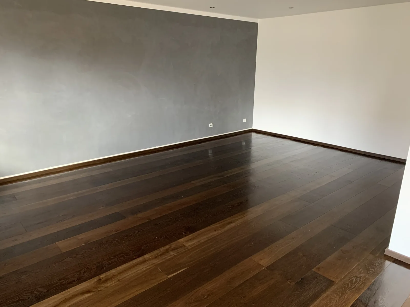 Fertig verlegtes dunkles Dielenparkett in einem leeren Wohnraum