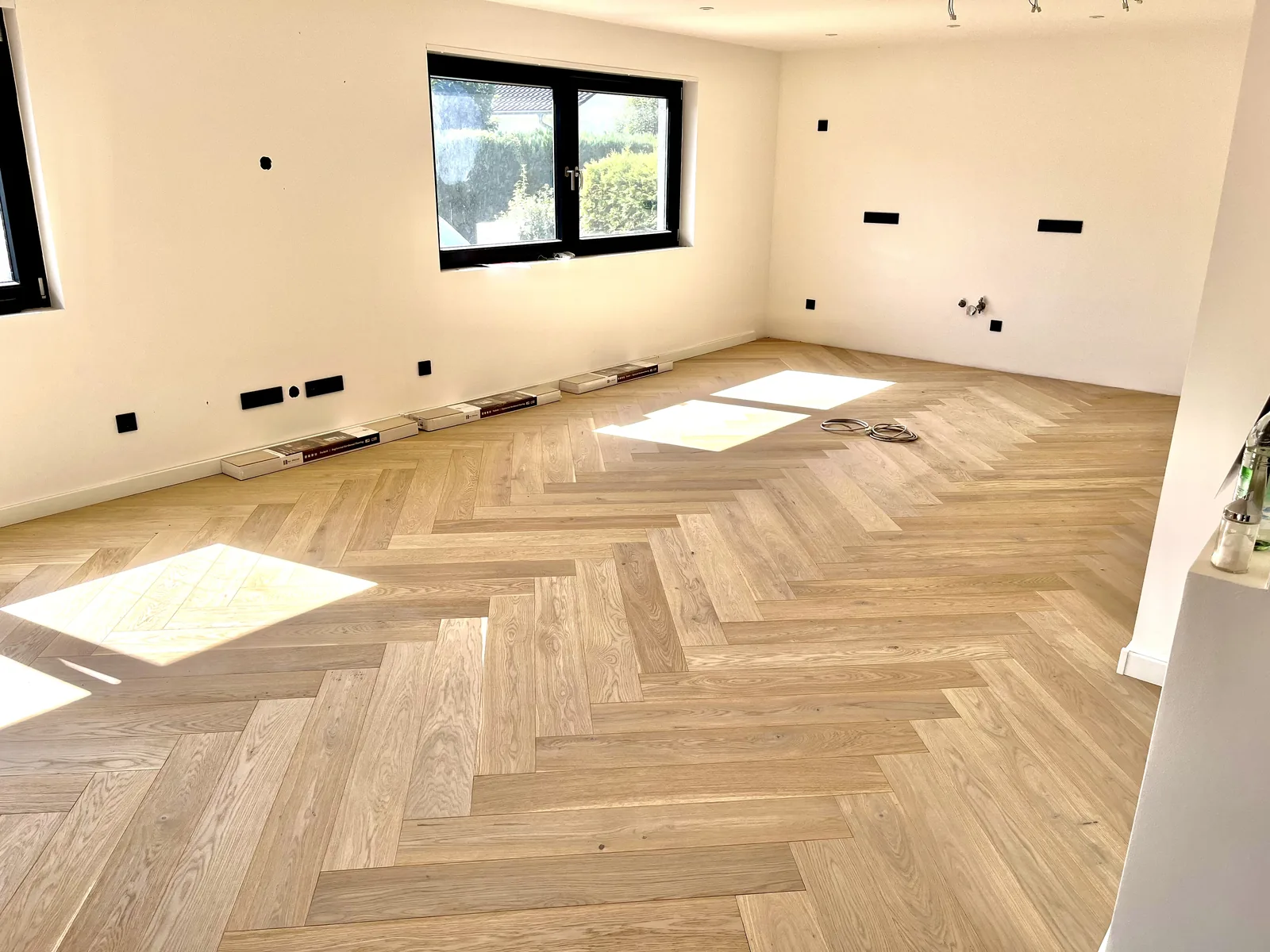 Fertig verlegtes Fischgrätparkett aus heller Eiche in einem leeren Zimmer