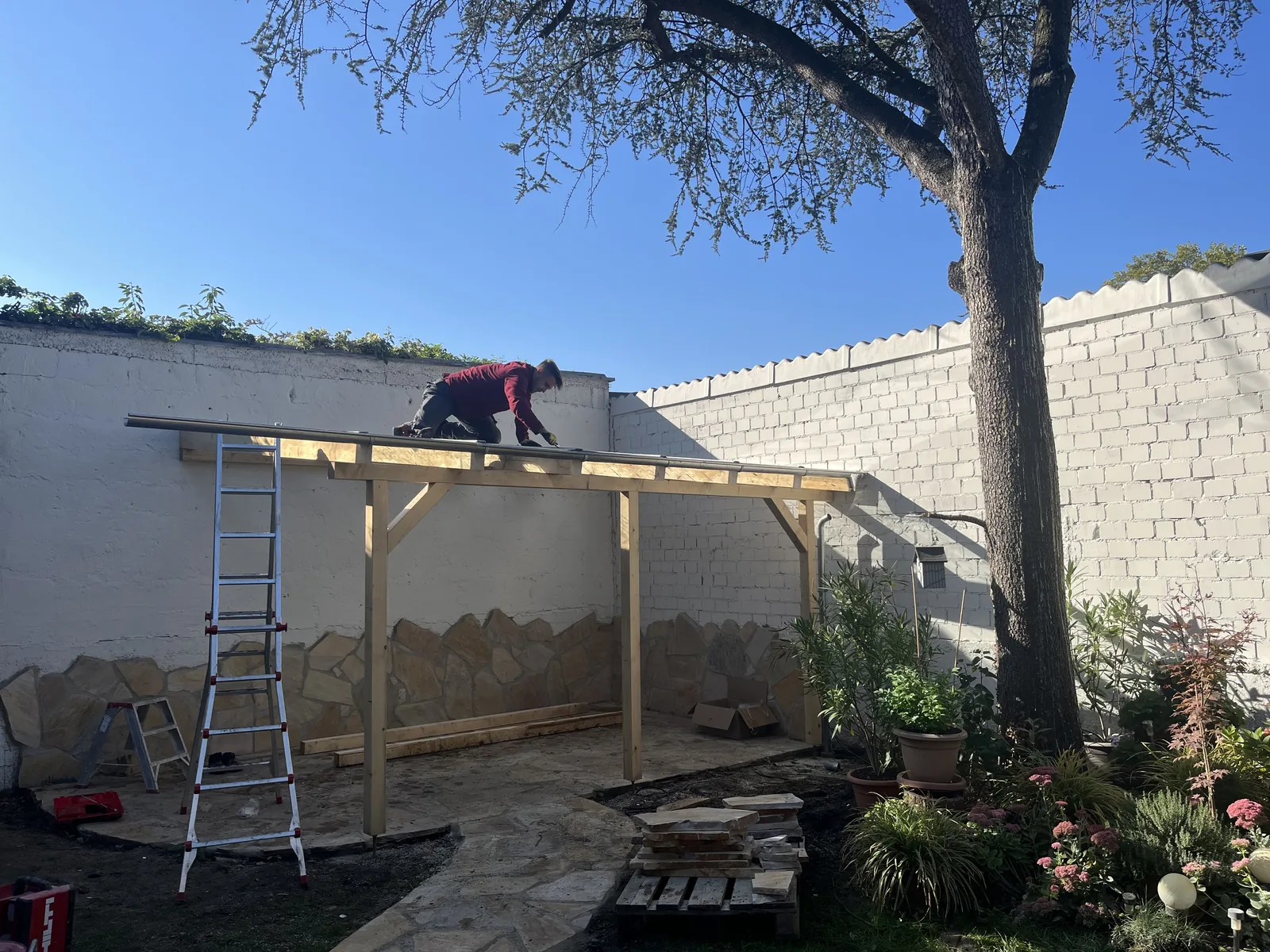 Holzkonstruktion einer Pergola im Bau über der fertigen Natursteinterrasse