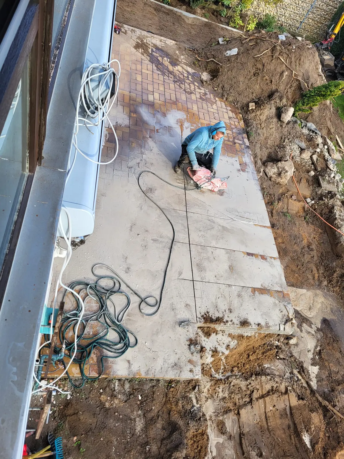 Betonplatte wird nass getrennt, Schnittlinien und Schlauch sichtbar