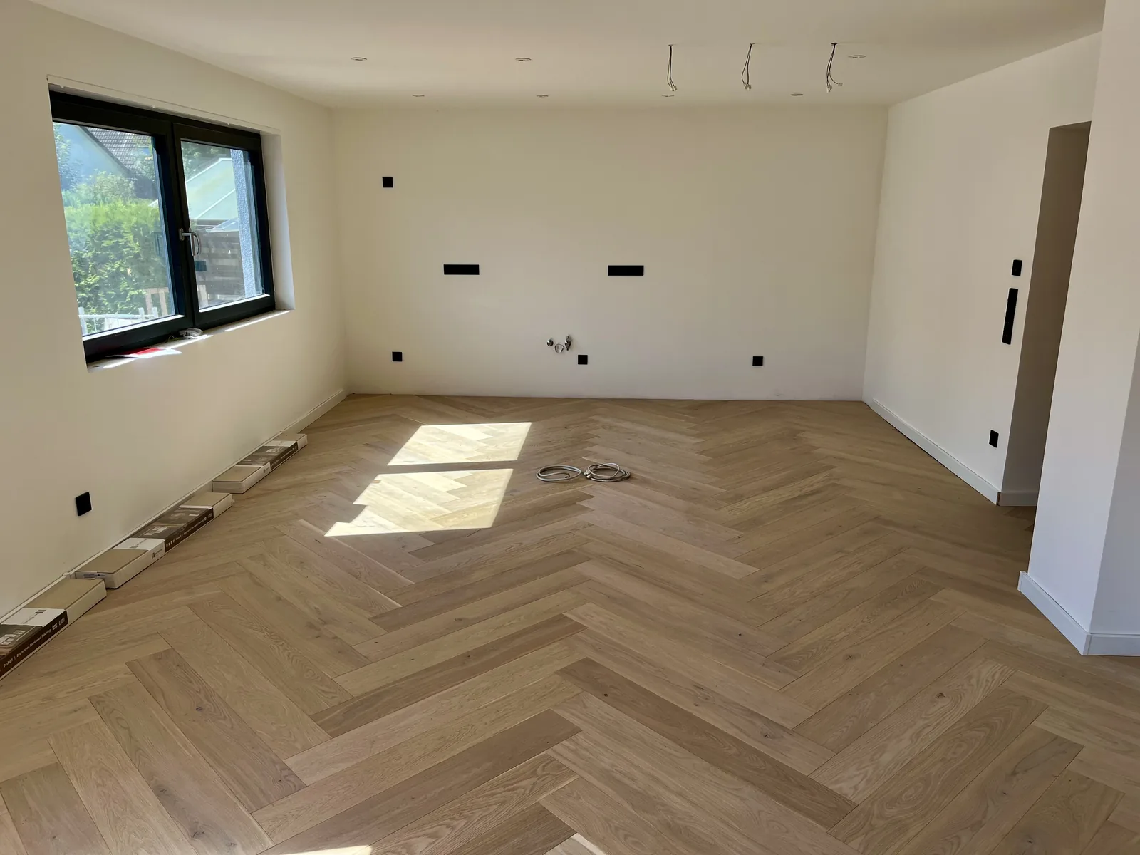 Fertiges Zimmer mit Fischgrätparkett aus Eiche, Sonnenlicht auf der Fläche