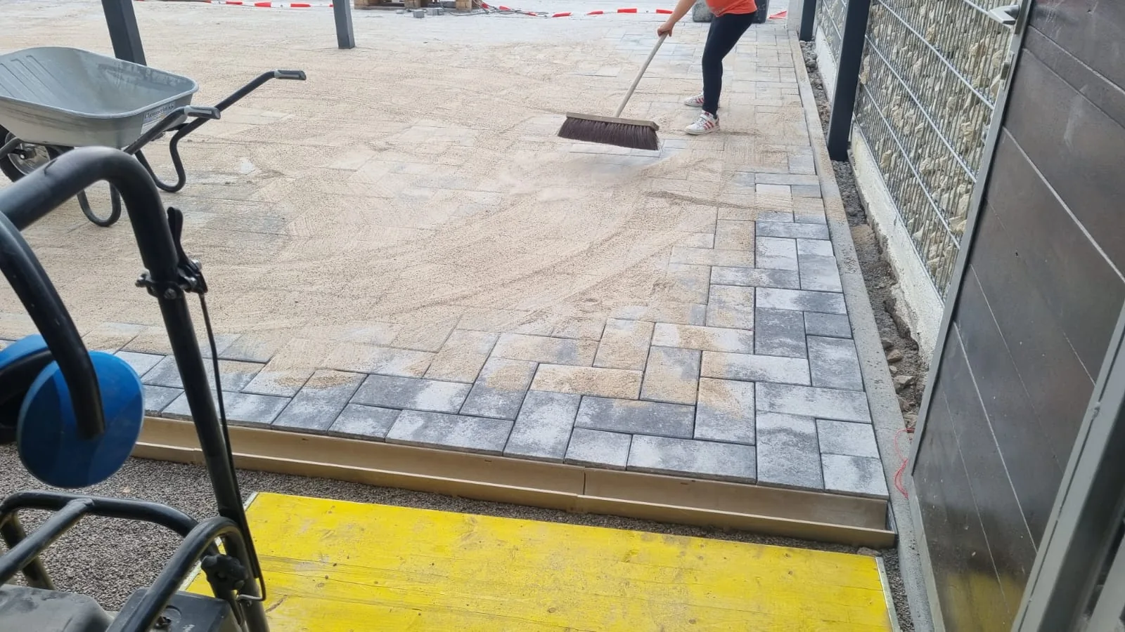 Fertig verlegte Pflasterfläche wird abgekehrt, Fugensand wird eingearbeitet