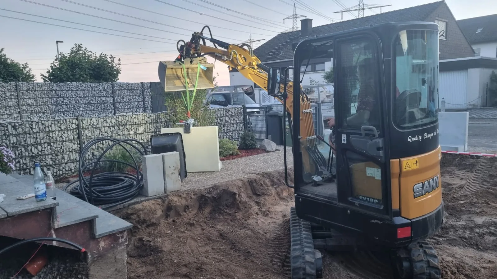 Minibagger bei Erdarbeiten vor der bereits gesetzten Gabionenwand