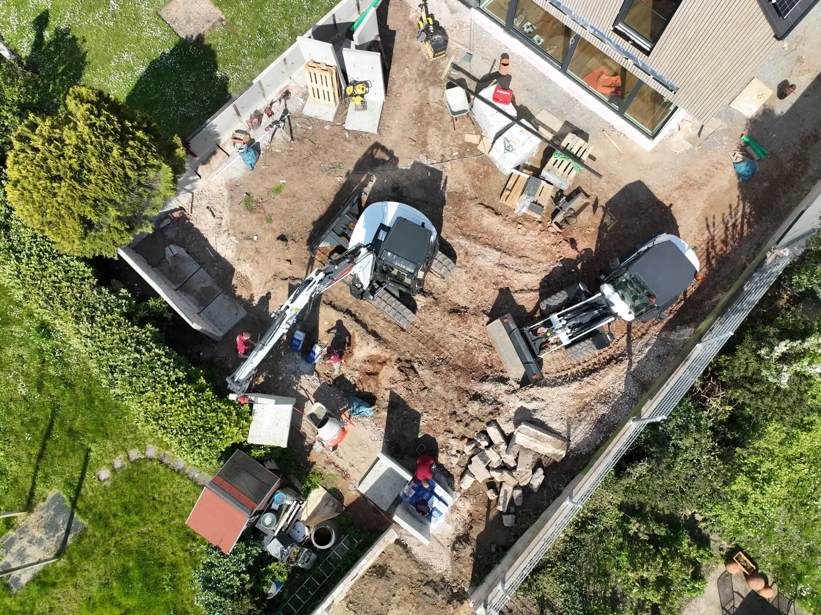 Luftaufnahme der Baustelle: Neubau, Erdaushub, Betonfertigteile und Baumaschinen