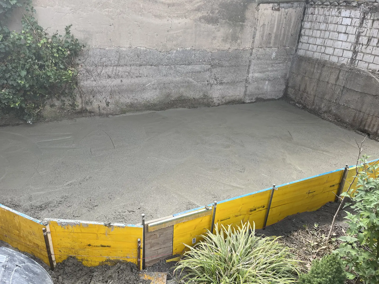Frisch gegossene Betonplatte als Unterbau der Terrasse, Schalung noch stehend