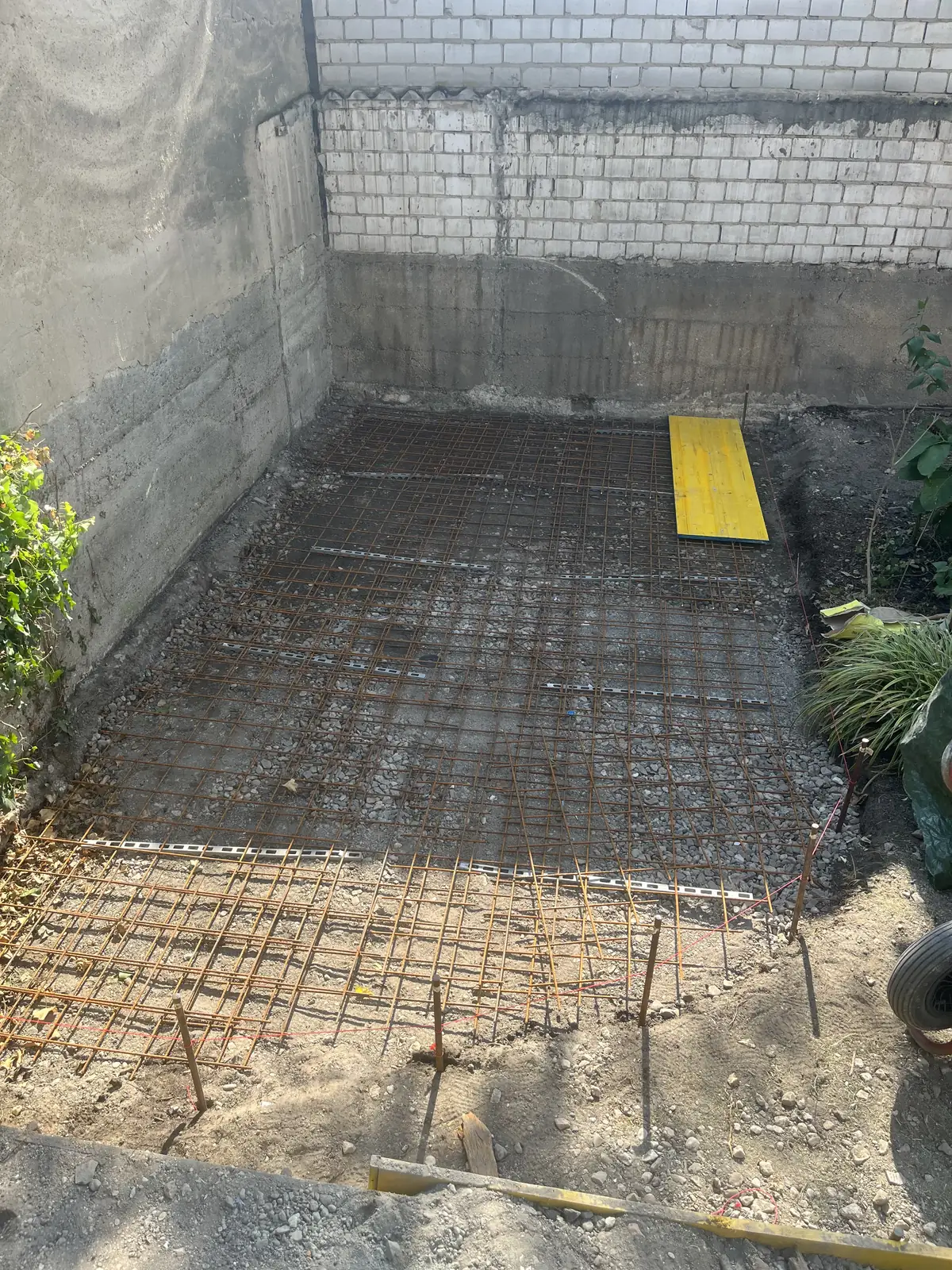 Bewehrungsmatten und gelbe Schalung auf dem vorbereiteten Untergrund der Terrasse