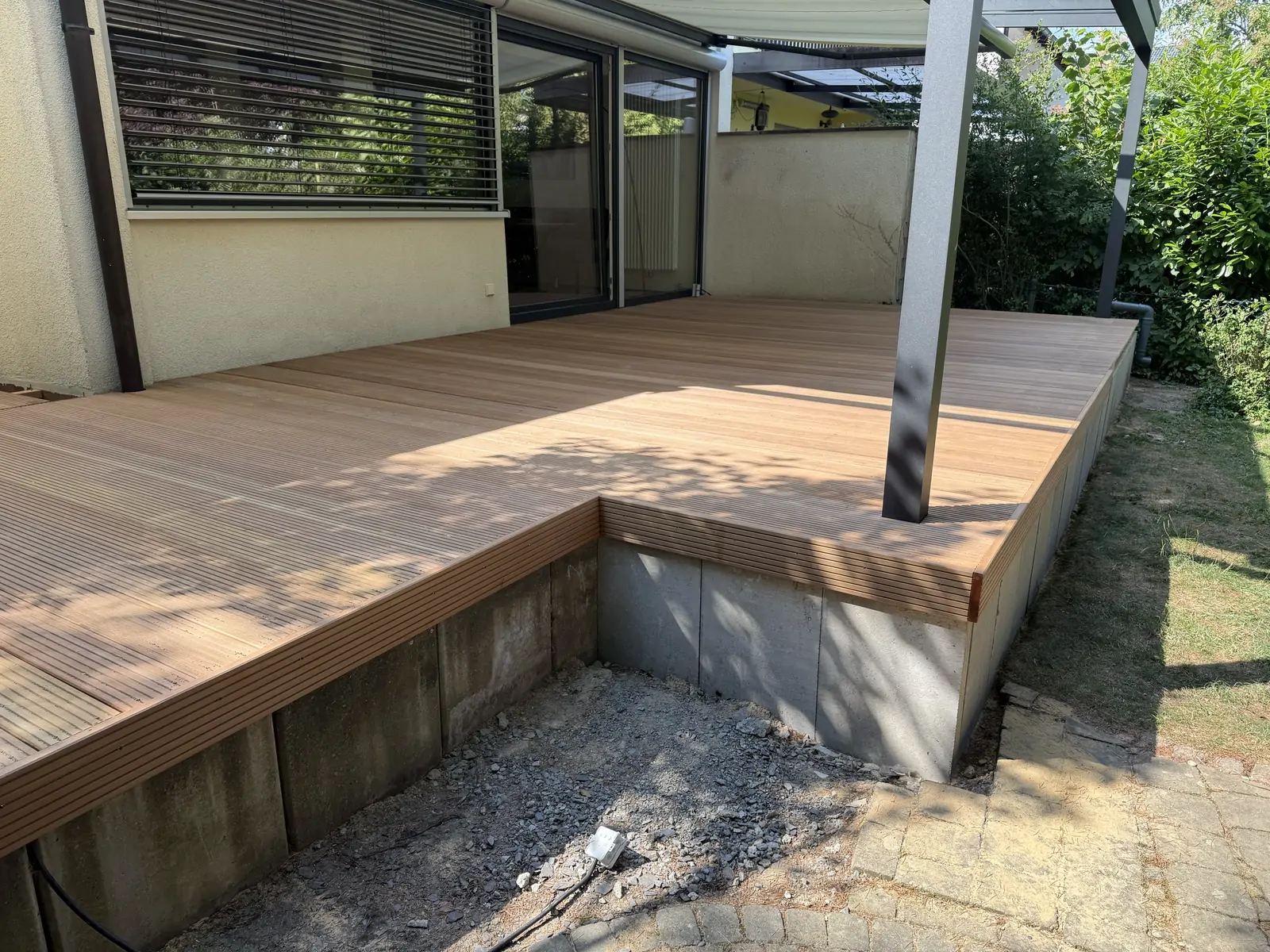Neu verlegte Terrassendielen auf der Unterkonstruktion mit Pergola-Stützen