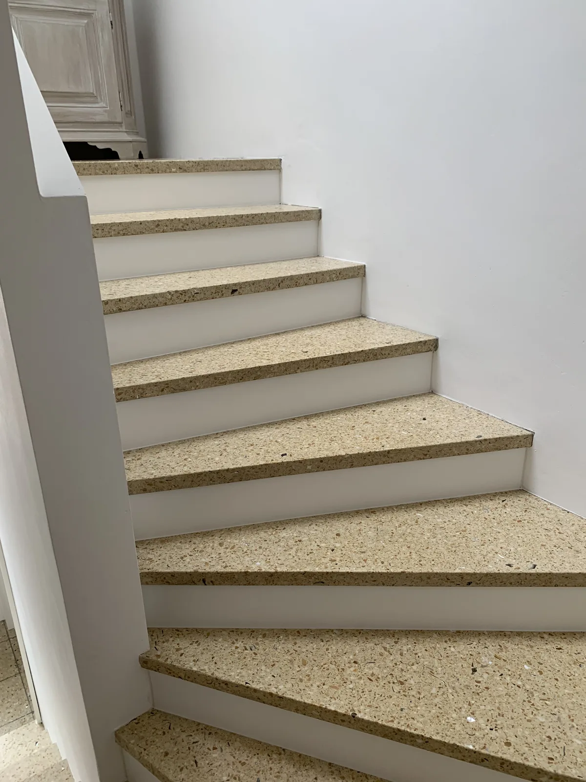 Gewendelter Treppenlauf mit hellen Terrazzostufen
