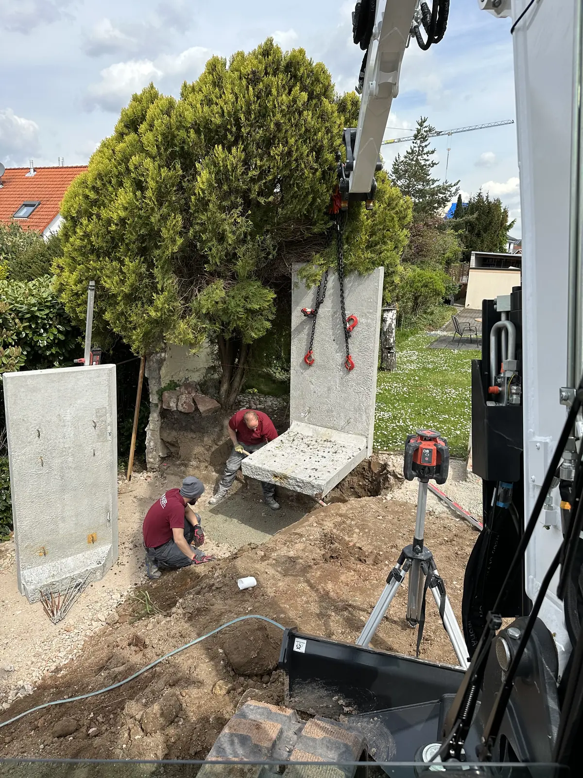 Betonfertigteil einer Stützwand hängt am Kran über der Baustelle