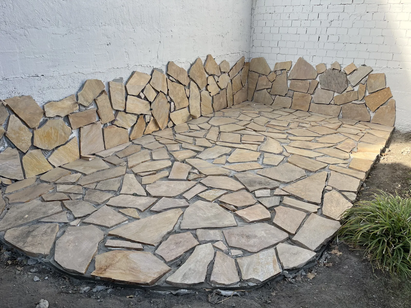 Fertige runde Terrasse aus Sandstein-Polygonalplatten mit Natursteineinfassung