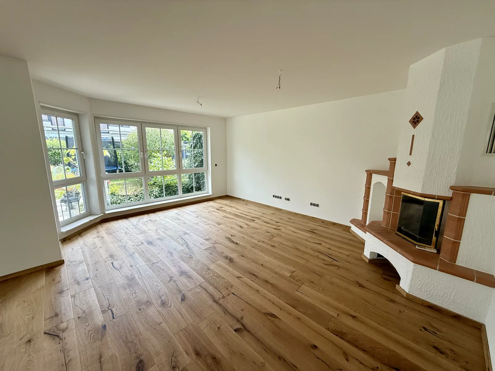 Fertiger Wohnraum mit Eichendielen, Kachelofen und großem Erkerfenster